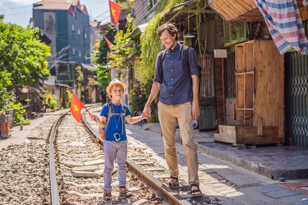 Father and son travelers walk around railway paths which go through residential area in hanoi city