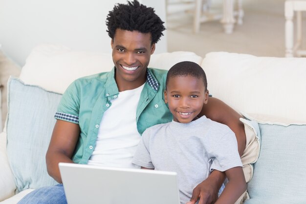 Father and son using laptop on the couch