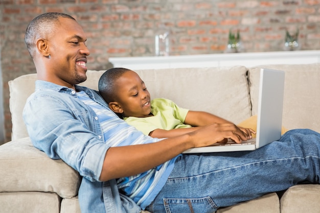 Father and son using laptop on the couch