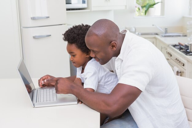 Father and son using laptop on the couch