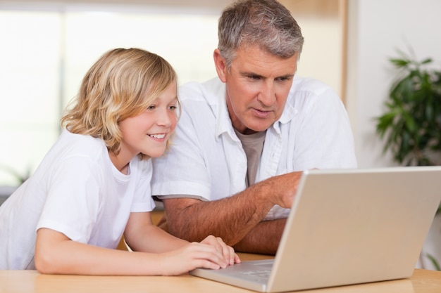 Father and son using laptop in the kitchen