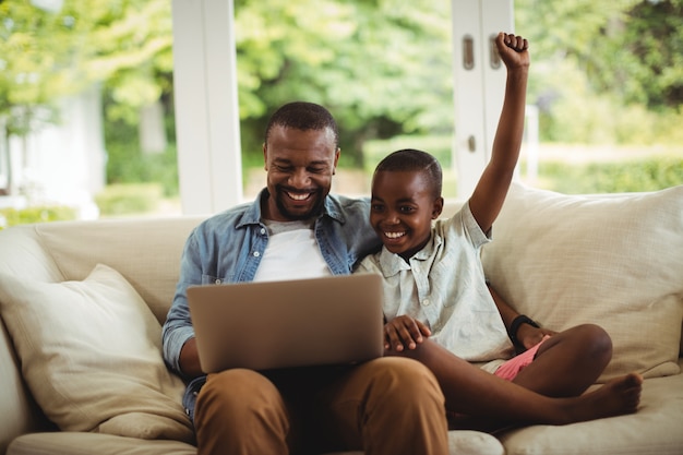 Father and son using laptop in living room