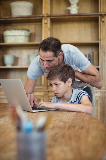 Father and son using laptop in study room