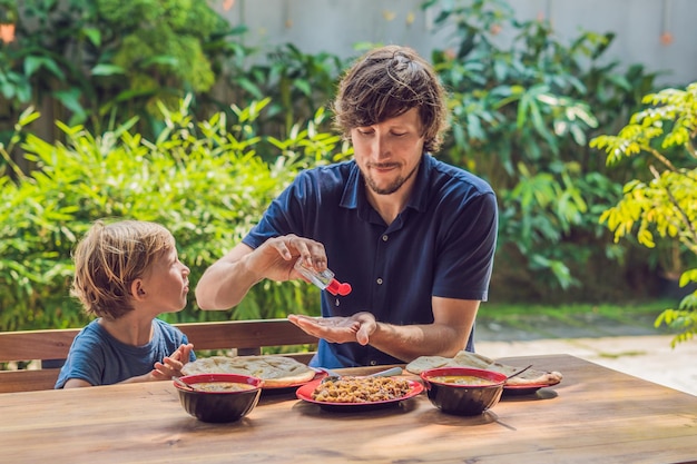 Father and son using wash hand sanitizer gel before eating in a cafe