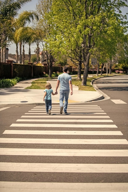 Father and son walk on zebra crossing family value parent leading small child boy