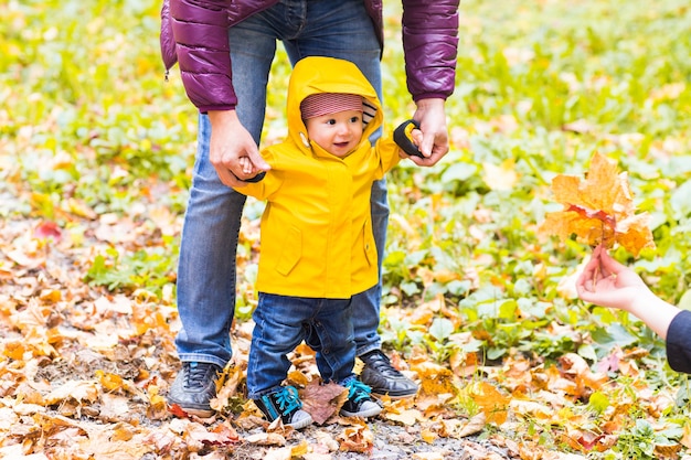 Father and Son walking. Baby taking first steps with father help in autumn garden in the city.