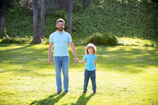 Father and son walking in park. happy family value. childhood and parenthood. parent leads little child boy on grass. dad with kid boy on summer day. parenting and fatherhood. fathers day.