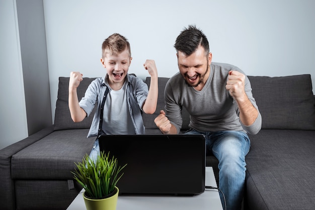 Отец и сын смотрят футбол в ноутбуке дома