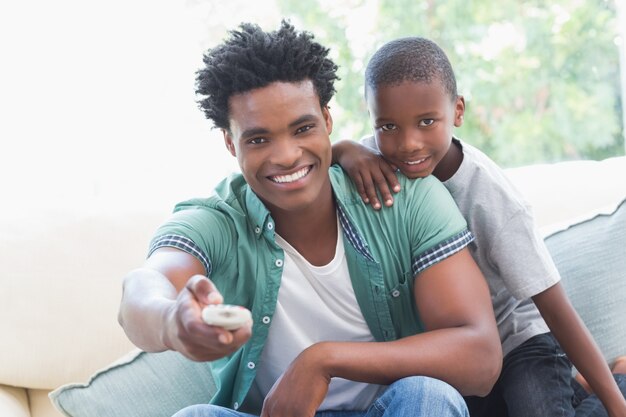 Photo father and son watching tv together on the couch