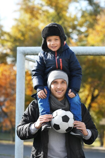 Photo father and son with ball on soccer pitch