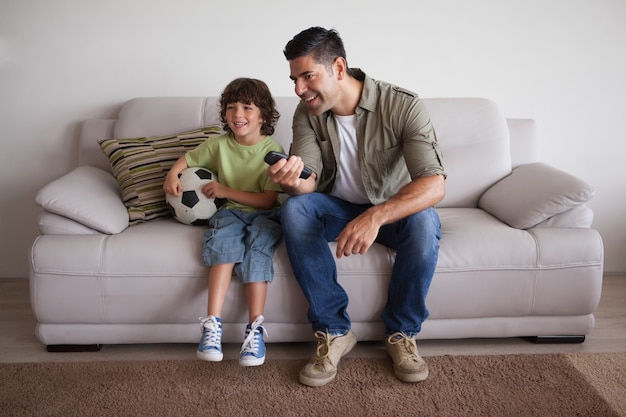 Father and son with football watching tv in the living room 