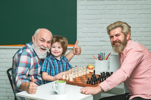 Padre e figlio con il nonno che giocano a scacchi tornano a scuola il giorno dei padri della generazione degli uomini