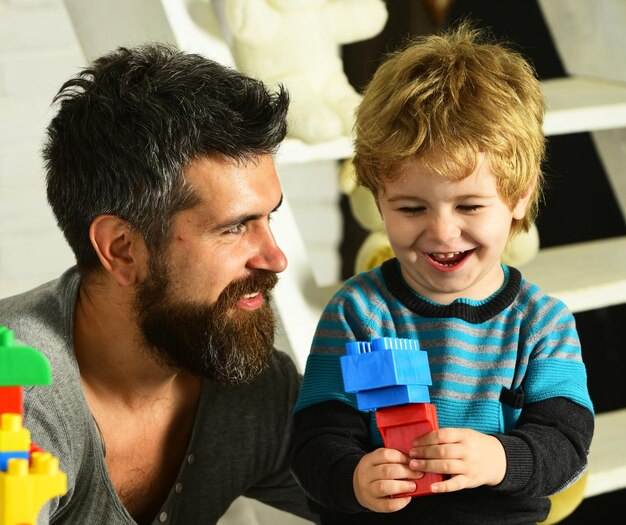 행복한 얼굴을 한 아버지와 아들이 다채로운 건축물을 만듭니다.