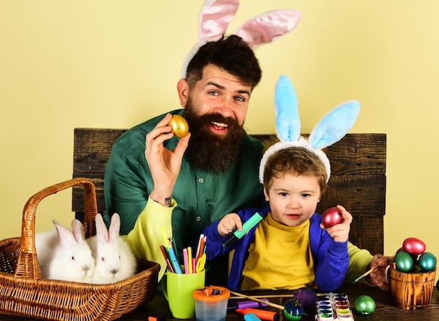 토끼 귀에 달걀 행복한 가족을 장식하기 위한 부활절 달걀을 그린 아버지와 아들