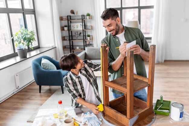 father and son with ruler measuring old table