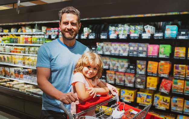 Father and son with shopping cart in the supermarket choosing food