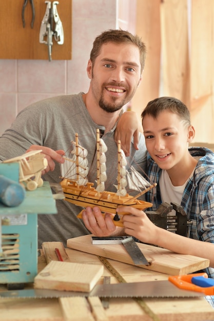 一緒に手で作られた木製の船を持つ父と息子