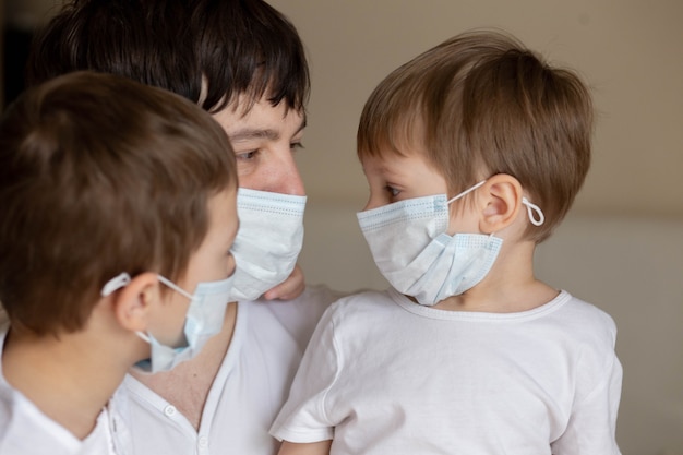 Padre e figli in mascherine mediche a casa. immagine con messa a fuoco selettiva. foto di alta qualità