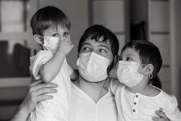 Father and sons in medical masks at home Image with selective focus