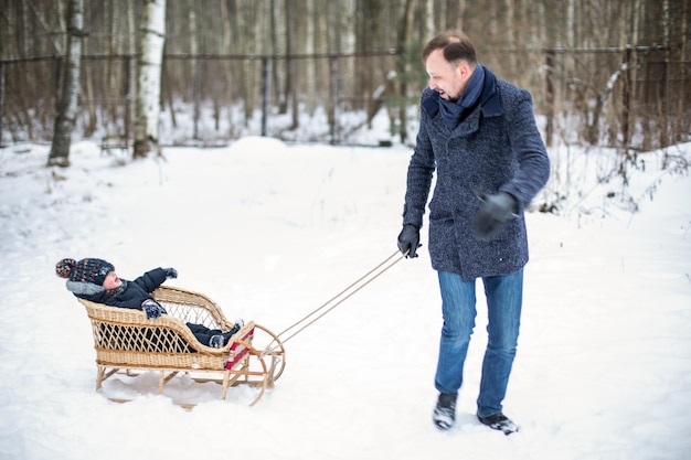 Foto un padre porta suo figlio a fare un giro nel bosco in inverno