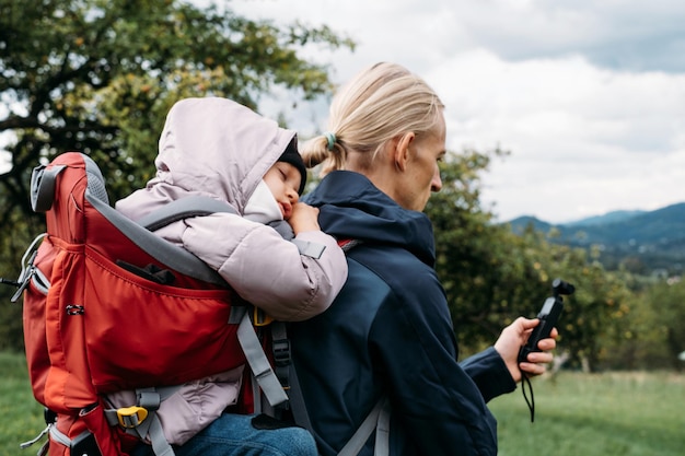 Father taking pictures while hiking with child in backpack