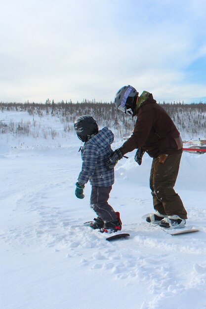 The father teaches the child to snowboard. winter fun on a frosty clear snowy day. joint family vacation