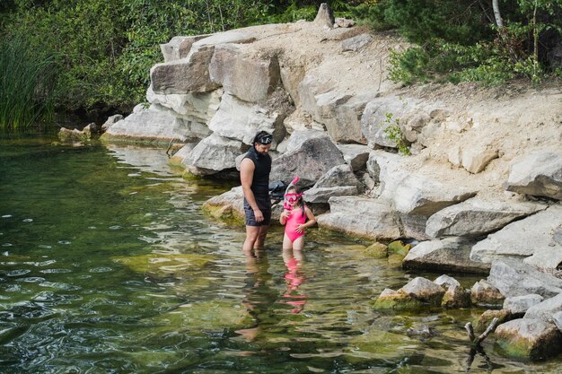 Foto un padre insegna a sua figlia a fare snorkeling su un lago in una giornata d'estate