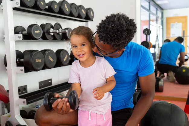 Father teaching daughter to lift dumbbell