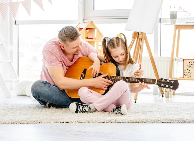 Father teaching daughter to play guitar