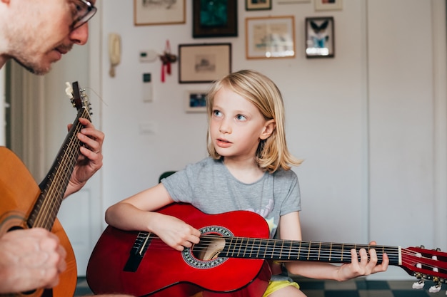 Padre che insegna a sua figlia a suonare la chitarra