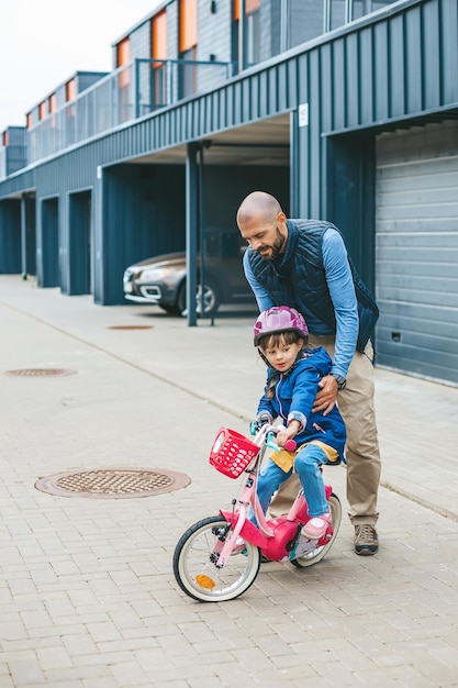 Father teaching his little daughter to ride a bicycle on the street