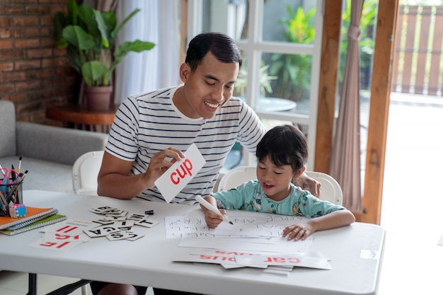 Father teaching letter to her daughter at home