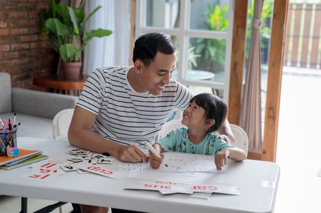 Father teaching letter to her daughter at home