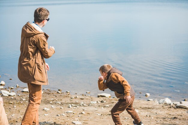 Father teaching little son throw rocks in water