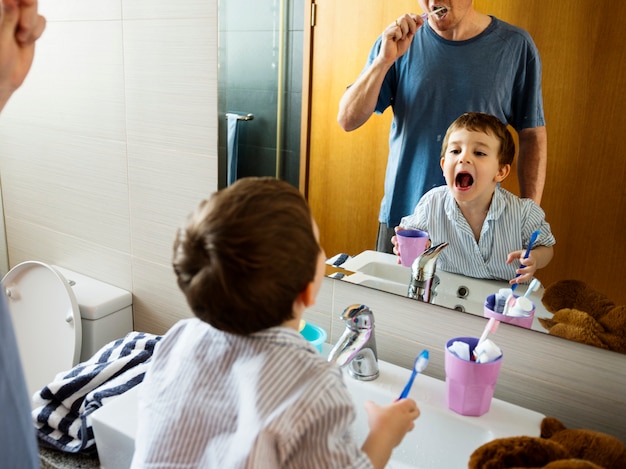 Photo father teaching the son how to brush his teeth