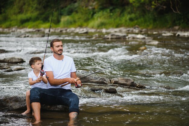 Father teaching son how to fish in the river