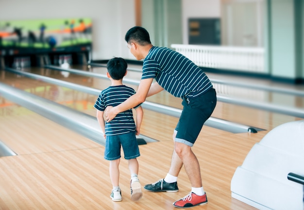 Father teaching son for play bowling at bowling club 