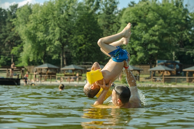 Отец весело бросает сына в воду