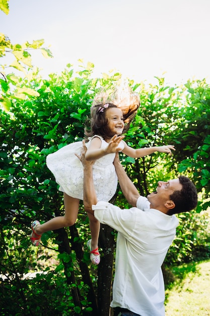 Father throws his daughter up standing in the forest