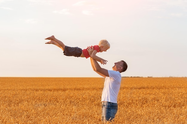 Father throws son Dad and child having fun outside Field of ripe wheat