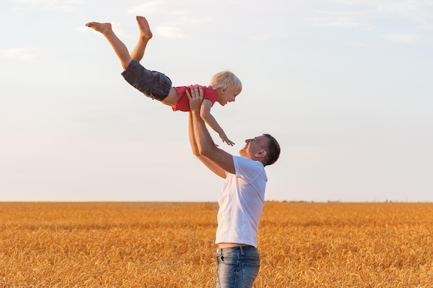 Father tosses child boy high into sky Dad and son having fun on outdoors