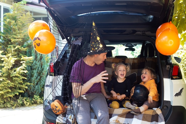 Father two kids celebrating halloween in car trunk autumn holiday