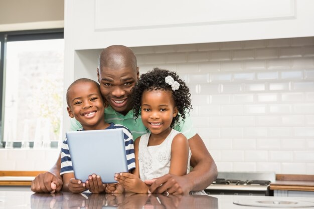 Generi facendo uso della compressa con i suoi bambini in cucina