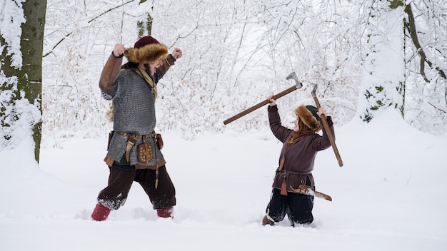 Photo father viking teaches his son for fighting holding in the hands axe