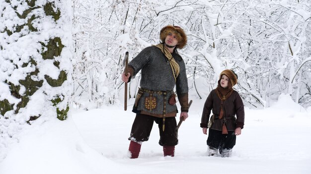 Photo father viking with his son in the winter forest