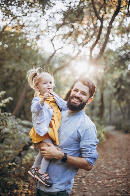 father walking in the autumn park together with his sweet little daughter enjoying the sunny weather