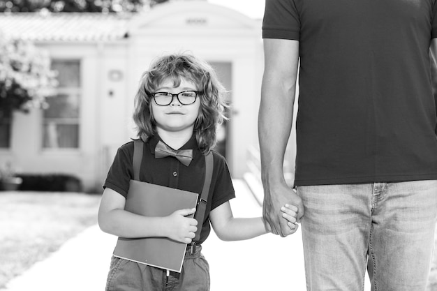 Father walking son to school parent and pupil of primary school schoolboy with backpack