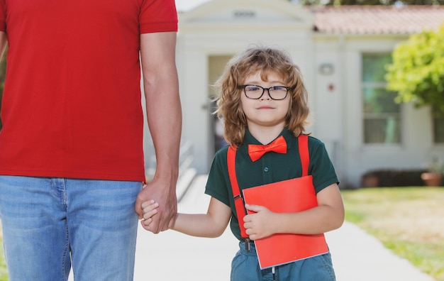 Father walking son to school parent and pupil of primary school schoolboy with backpack