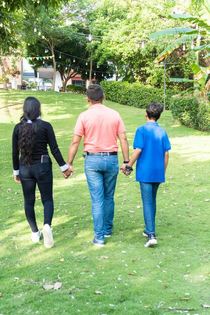 Father walking through a field with his children holding his hands