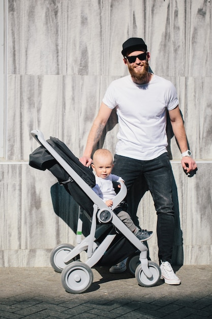 Father walking with a stroller and a baby in the city streets